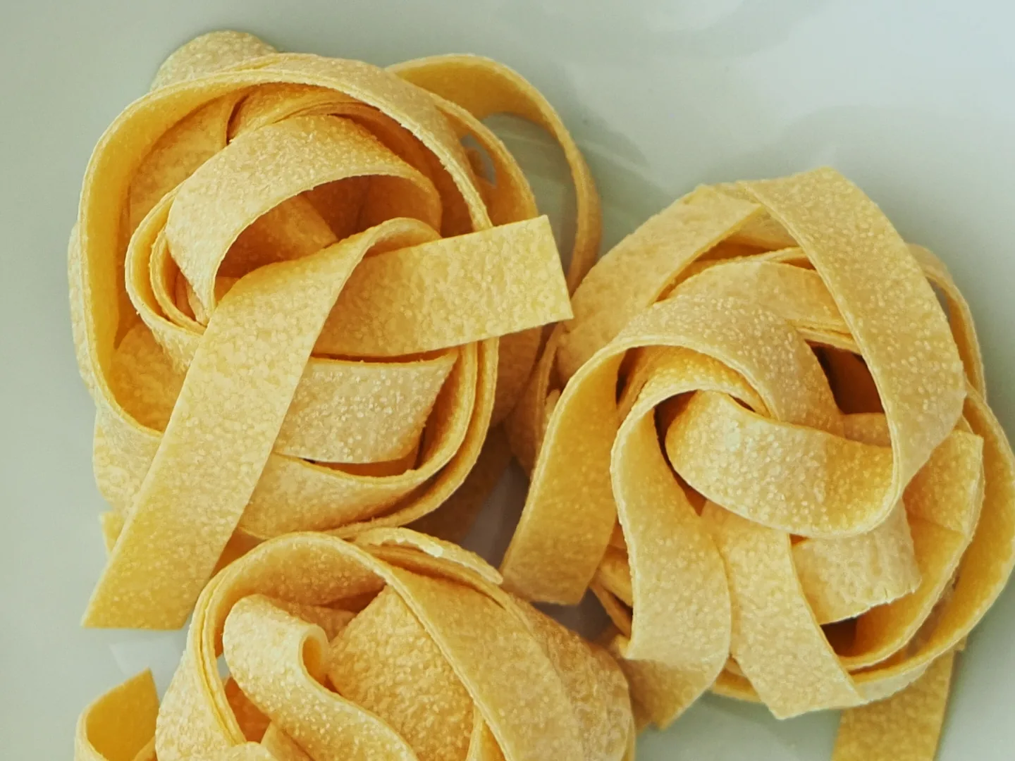 Primo piano di pappardelle all'uovo Antichi Sapori: la superficie ruvida e porosa della trafila al bronzo Primo piano di pappardelle all'uovo Antichi Sapori: la superficie ruvida e porosa della trafila al bronzo