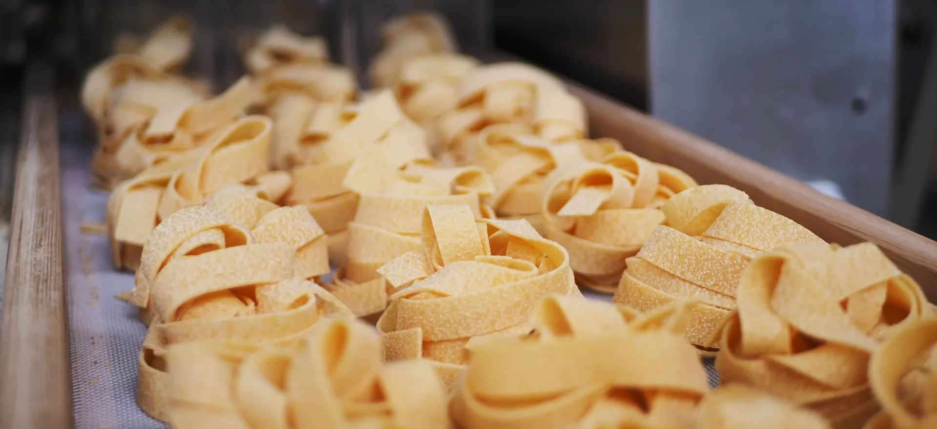 Nidi di pasta secca all'uovo su un tavolo di legno davanti al grano